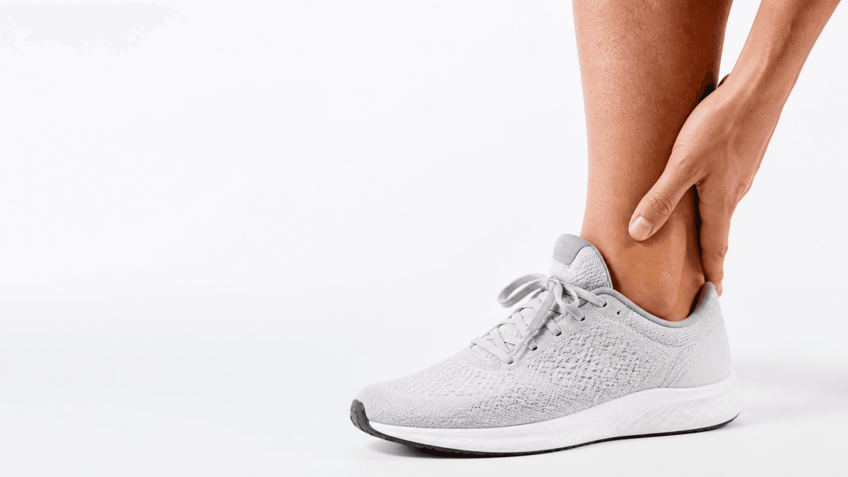 Person gently supporting an ankle above a running shoe