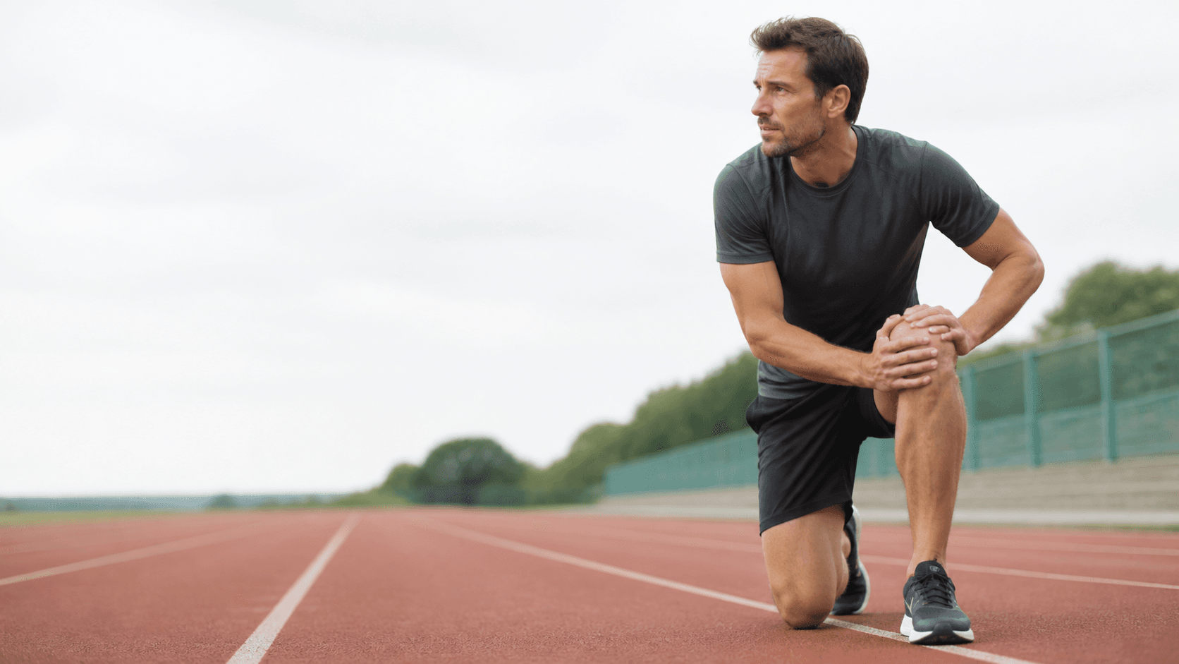 Runner pausing on a track and supporting one knee