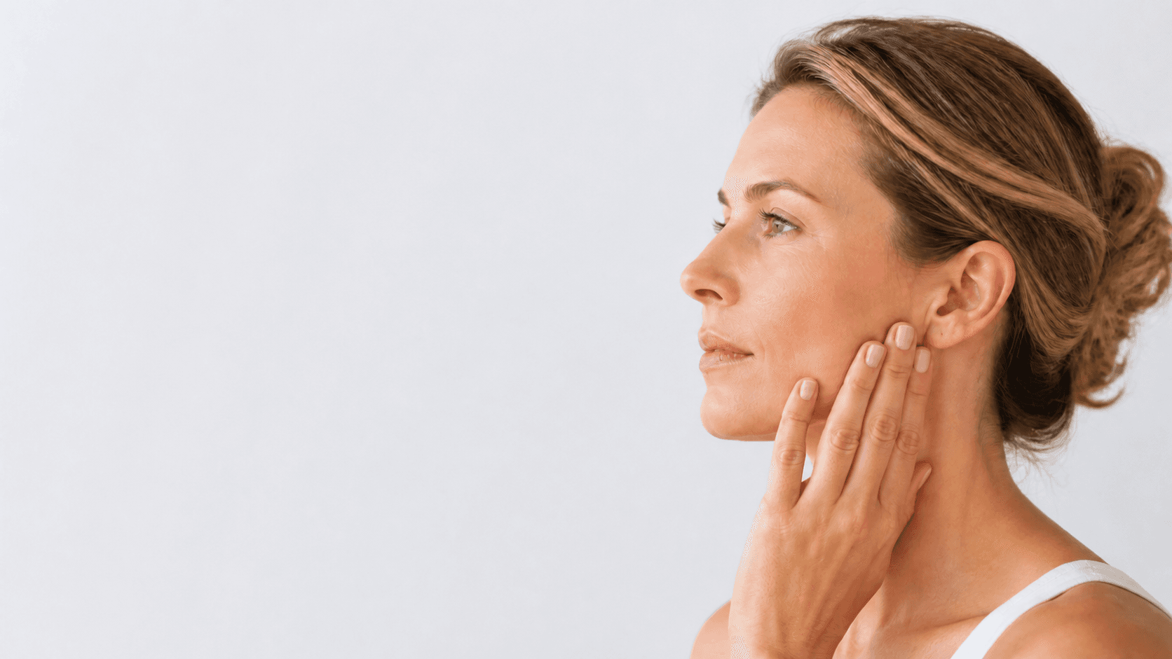 Person gently resting fingers along the jaw below the ear